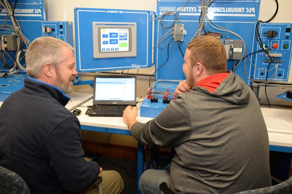 A professor demonstrating how to use a machine to his student